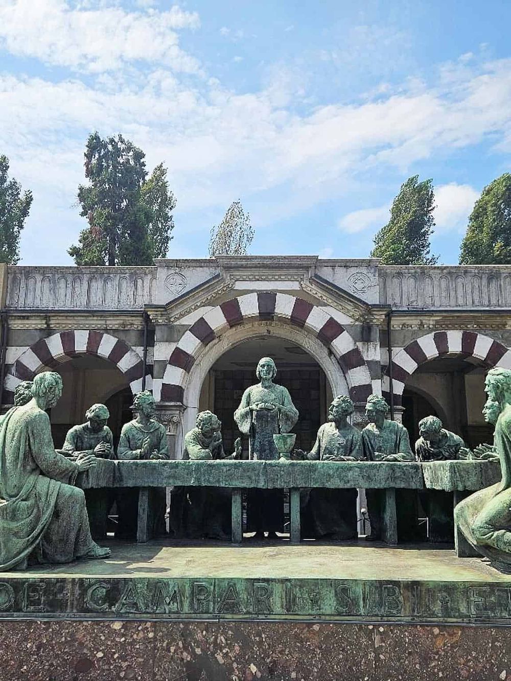 Bronze statue of the Last Supper at Quest for Directions, featuring iconic religious artwork on building facade.