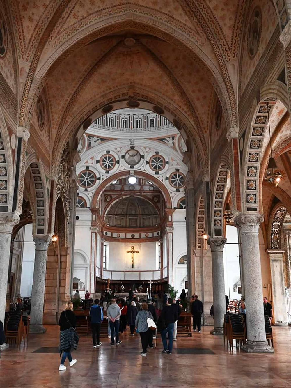 Intricate church interior with high vaulted ceilings, detailed architecture, and worshippers.
