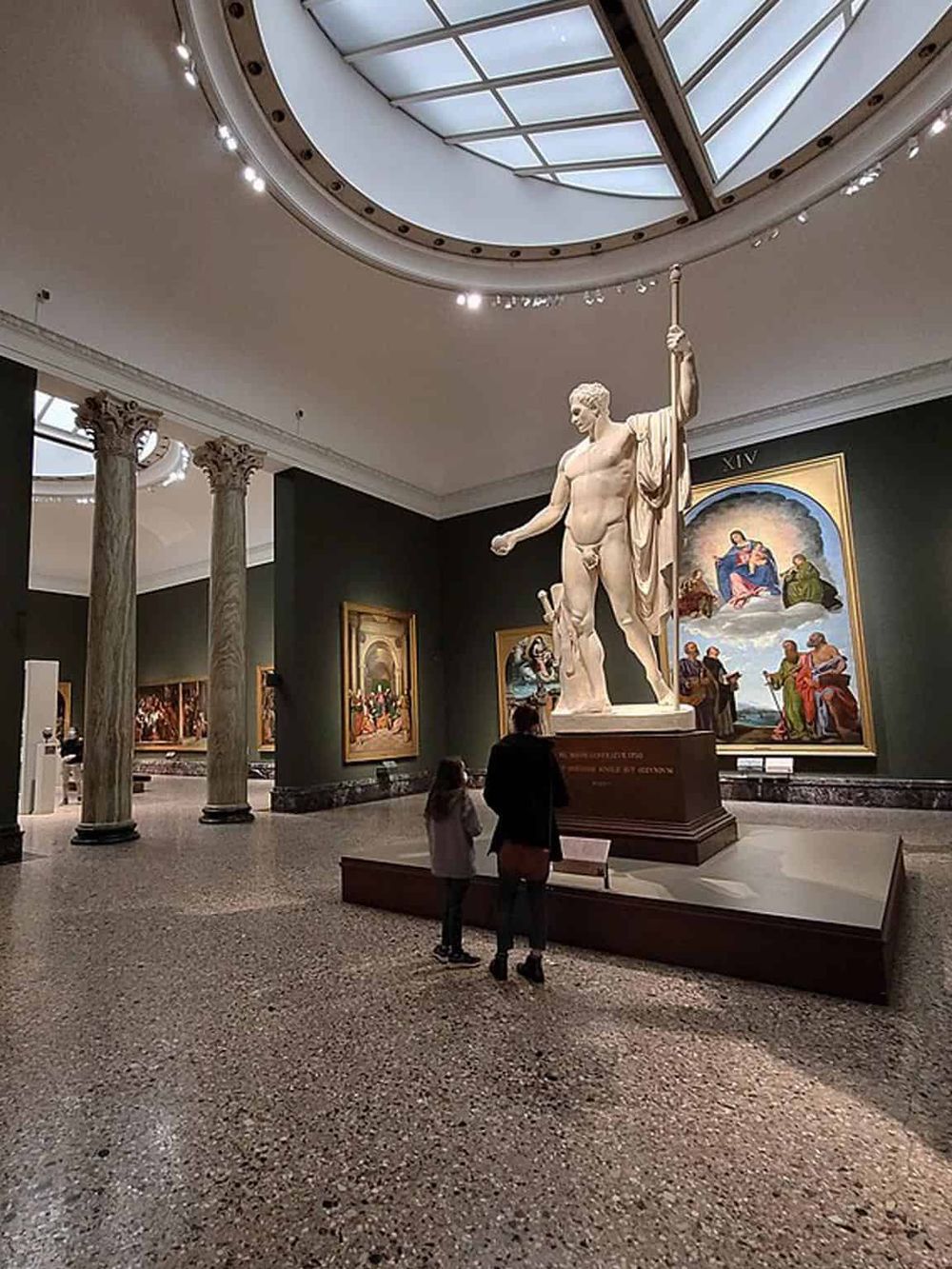 Ancient Greek sculpture in museum interior with classical columns and artwork, showcasing historical art.