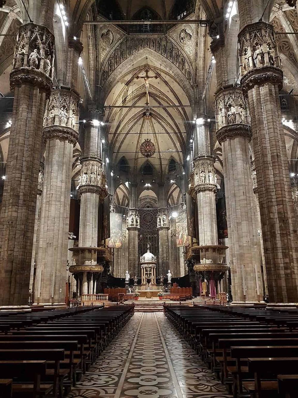 Ornate Gothic cathedral interior with high vaulted ceilings, intricate pillars, and detailed religious sculptures.