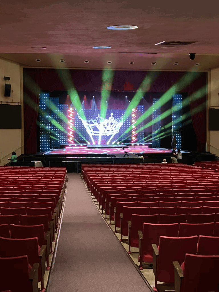 Vivid concert stage with colorful lighting and LED screens in an indoor theater setting.