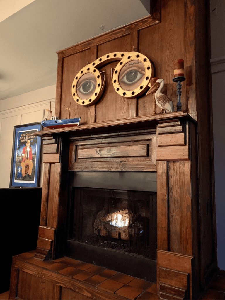 Intriguing fireplace mantel with unique eyes artwork and vintage décor in warmly lit room.