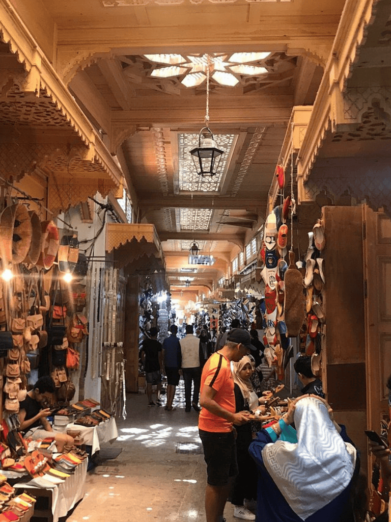 Colorful bazaar with handcrafted goods, shoes, and accessories in traditional architecture setting.