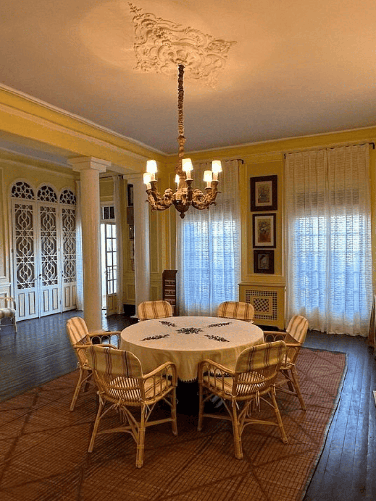 Elegant dining room with round table, wicker chairs, chandelier, and vintage decor for a cozy home setting.