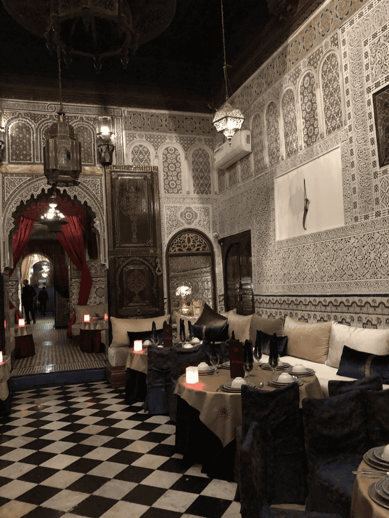 Elegant Moroccan-style restaurant interior with intricate wall patterns and cozy dining setup.