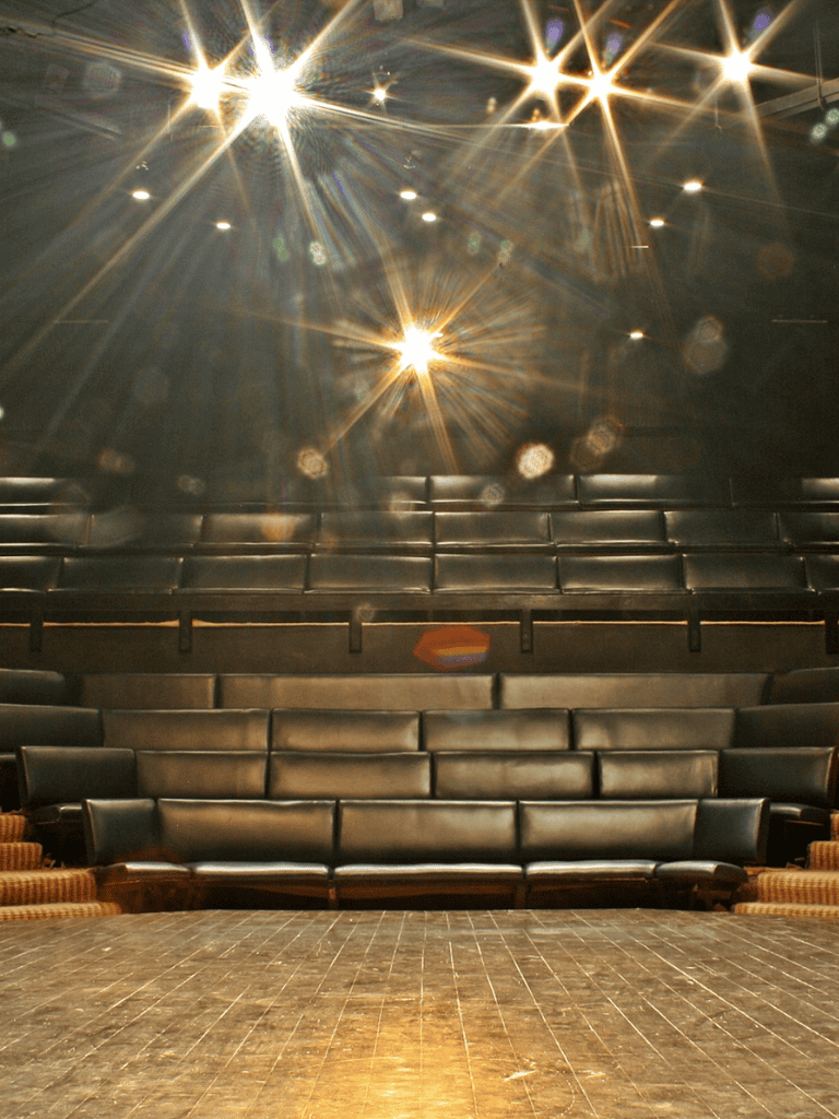 Bright stage lights illuminate an empty theater auditorium for events or performances.