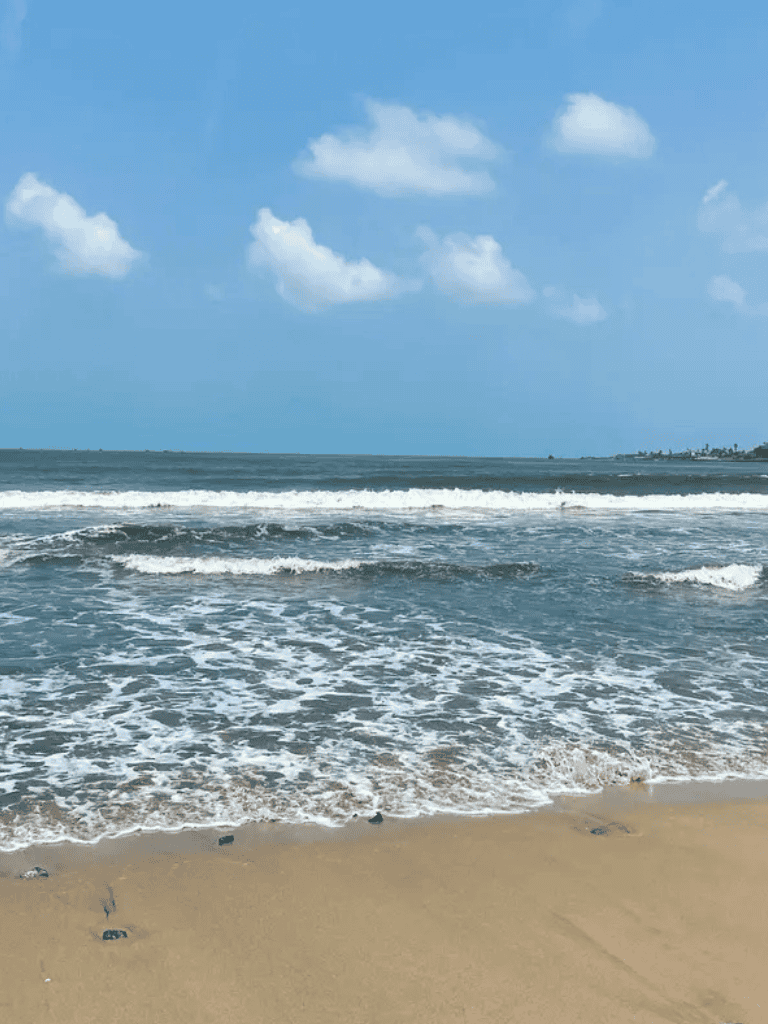 Serene beach with blue sky, gentle waves, and sandy shore perfect for seaside relaxation.