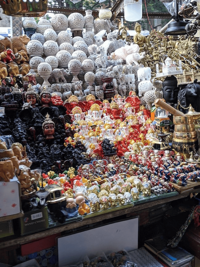 Colorful collection of statues and souvenirs, including elephants and deities, at a market stall in Thailand.