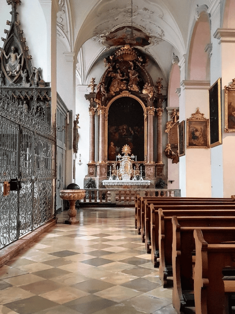 Intricate church altar with religious paintings, ornate gold accents, and wooden pews in a historic sacred space.