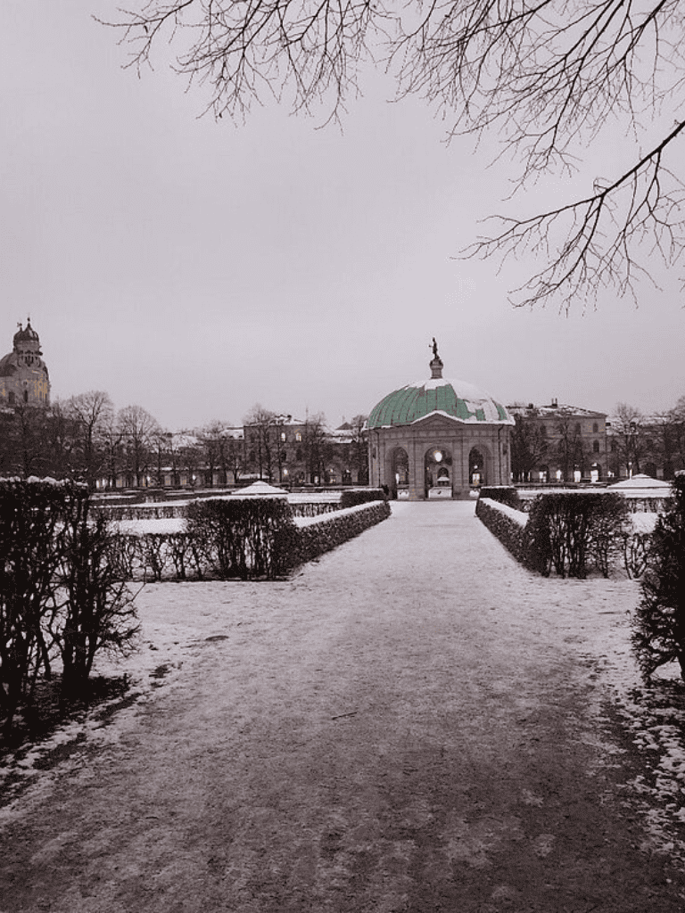 Bright winter park scene with historic pavilion and snow-covered pathways, perfect for sightseeing and outdoor exploration.
