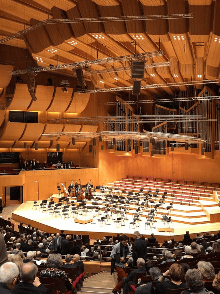 Concert hall interior with wooden acoustic panels and stage setup for orchestra seating.