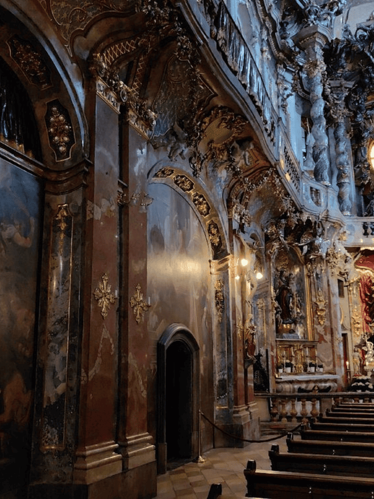 Opulent Baroque church interior with gold accents and intricate architectural details.