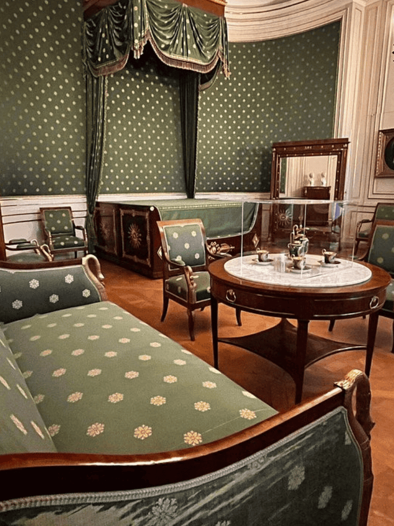 Ornate vintage parlour with green floral upholstery and elegant drapes, ideal for historical venue photos.