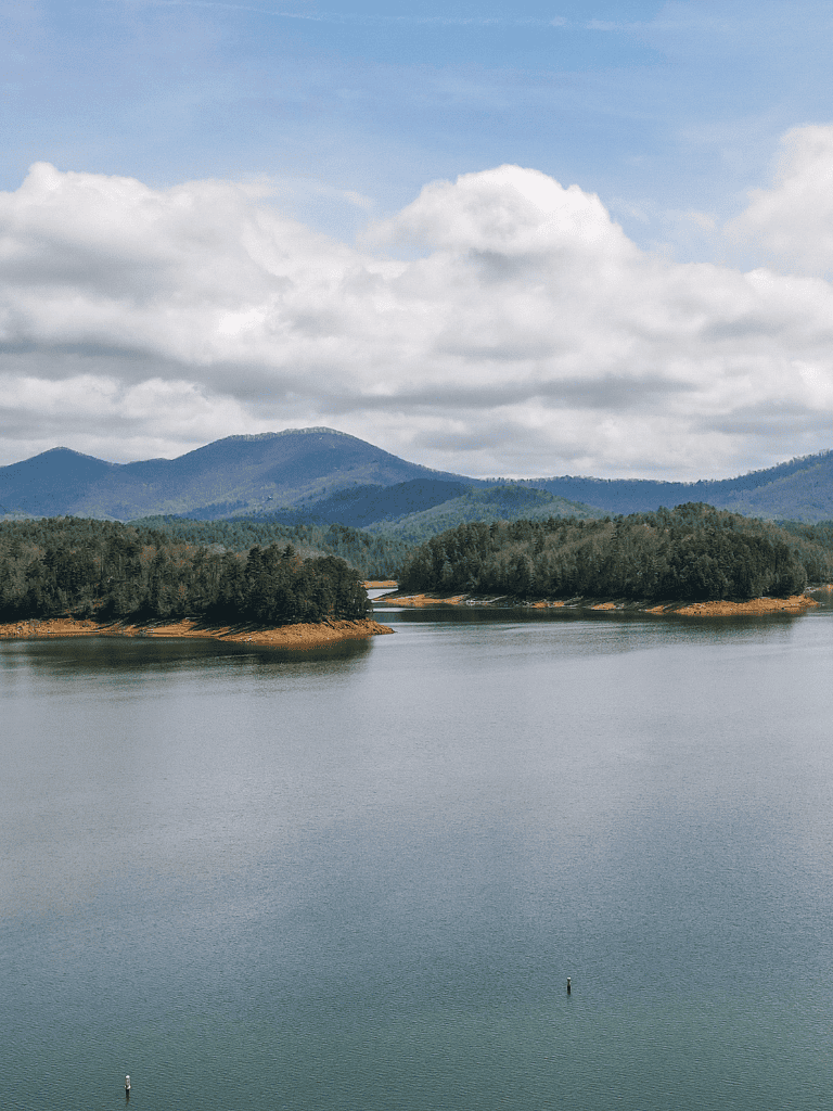 Serene lake with forested islands and mountain backdrop, ideal for outdoor adventures and scenic exploration.