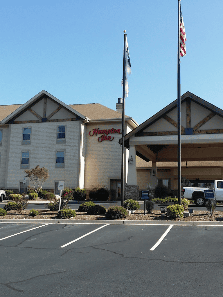 Flagpoles outside Hampton Inn hotel with blue sky.