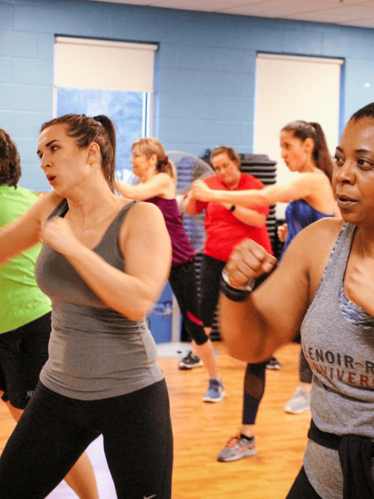 Wide-angle shot of women participating in a fitness class, demonstrating strength and motivation at QuestForDirections.