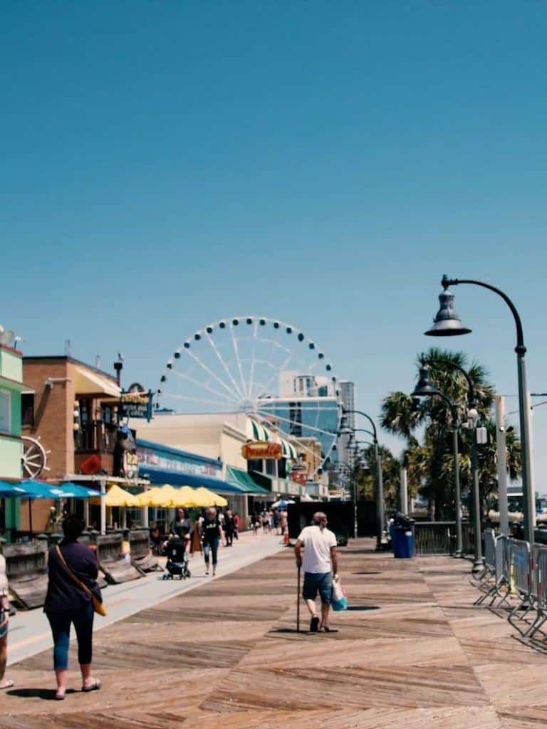 Ferris wheel and bustling seaside promenade at QuestForDirections, a popular tourist destination.