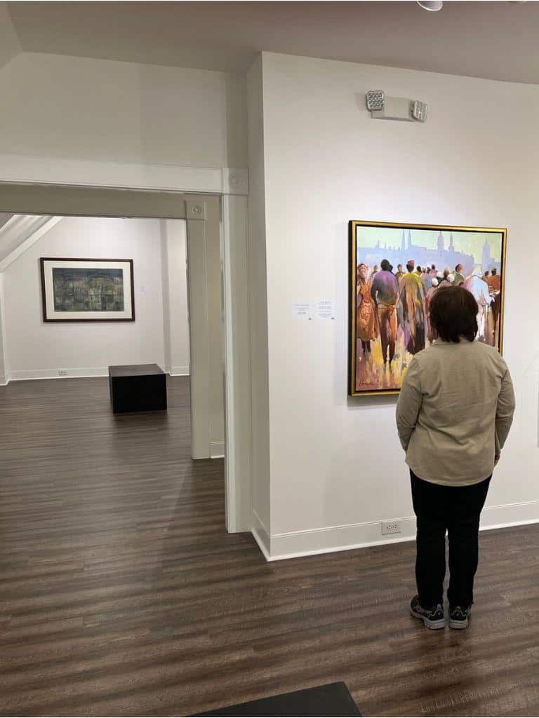 Colorful art gallery exhibition featuring a woman viewing a painting, showcasing modern artwork and museum ambiance.