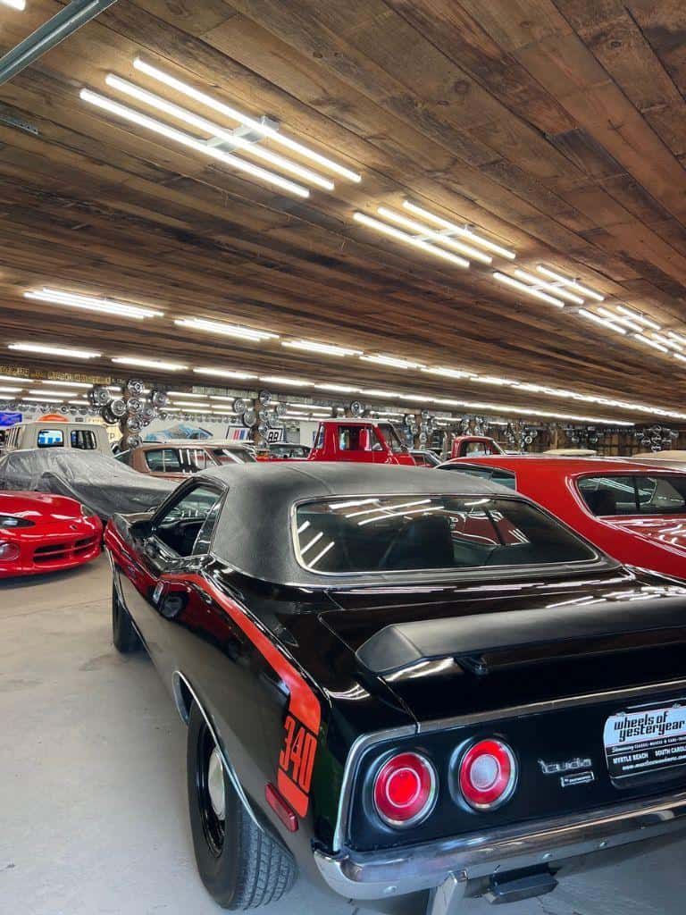 Vintage muscle cars and classic vehicles in a spacious showroom warehouse.