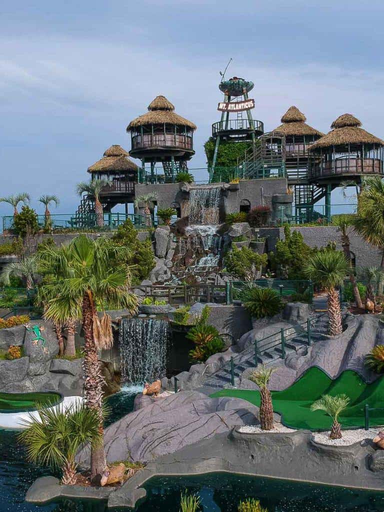 Colorful water park with waterfalls, palm trees, and themed structures at QuestForDirections destination.