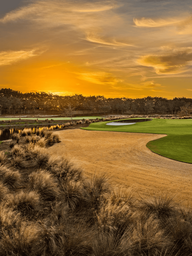 Golden sunset over a scenic golf course with lush green fairways and sand traps, perfect for outdoor sports.