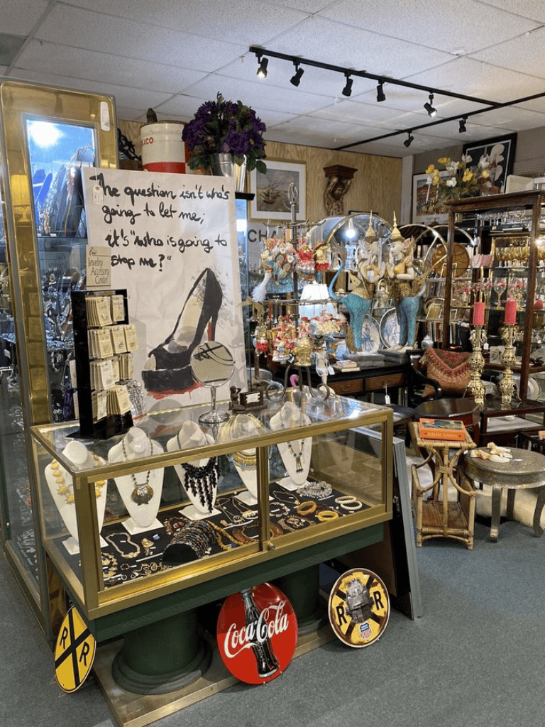 Antique jewelry display with vintage accessories and decorative signs in a thrift store.