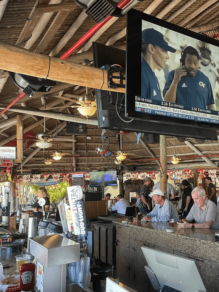 Relaxed sports bar with multiple TV screens, lively atmosphere, and bar seating, perfect for watching games and enjoying drinks.