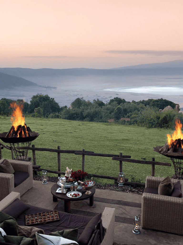 Cozy outdoor terrace with fire pits overlooking scenic mountains and lake at sunset, perfect for relaxation and gatherings.