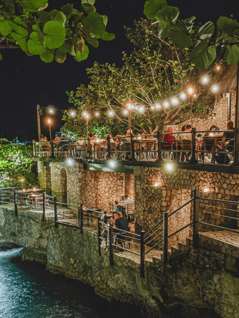 Al fresco dining at night with string lights overlooking a waterway, a perfect destination from QuestForDirections.