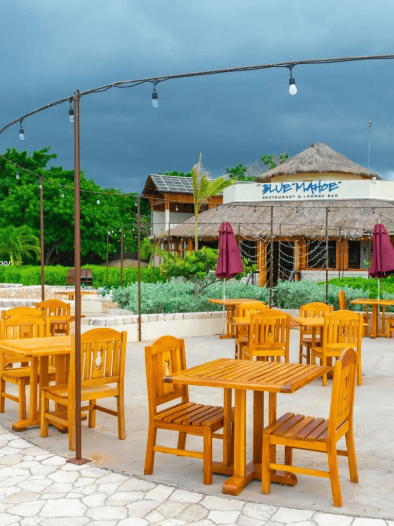Aluminum outdoor string lights over wooden tables at a tropical restaurant patio, Blue Mambo.