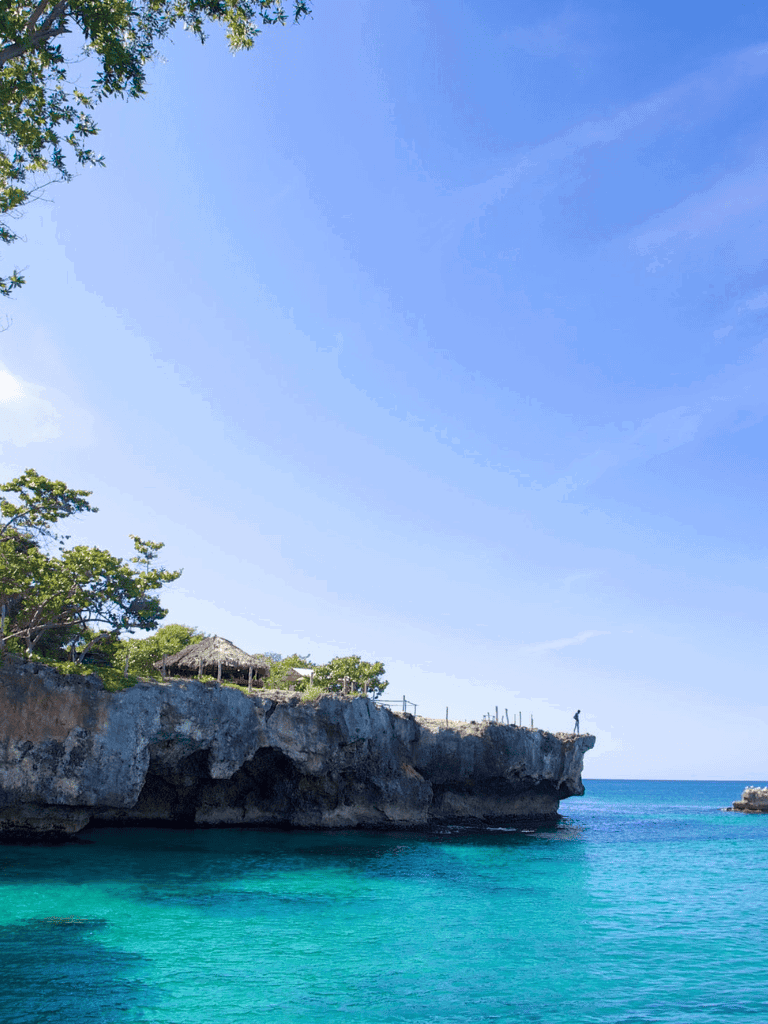 Stunning ocean cliff view with turquoise waters and clear sky, perfect for travel and adventure.