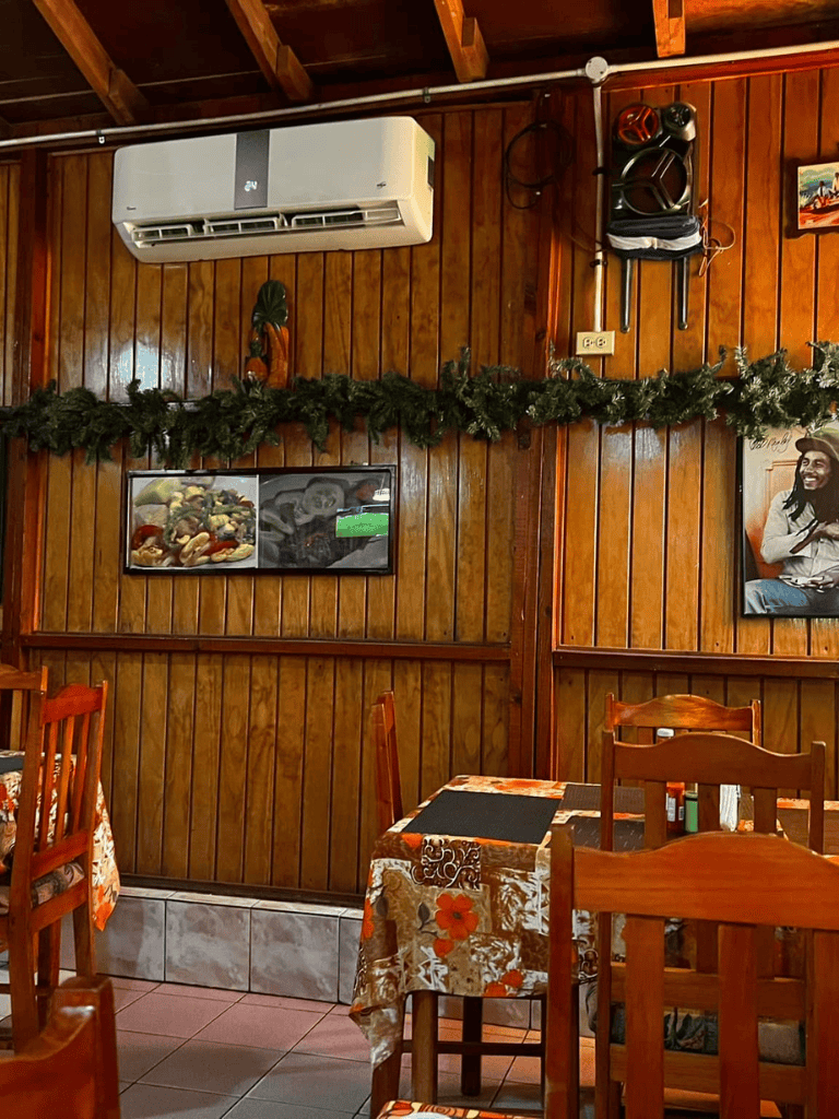Air conditioning unit on wooden wall with holiday garland and restaurant decor, cozy indoor dining setting.