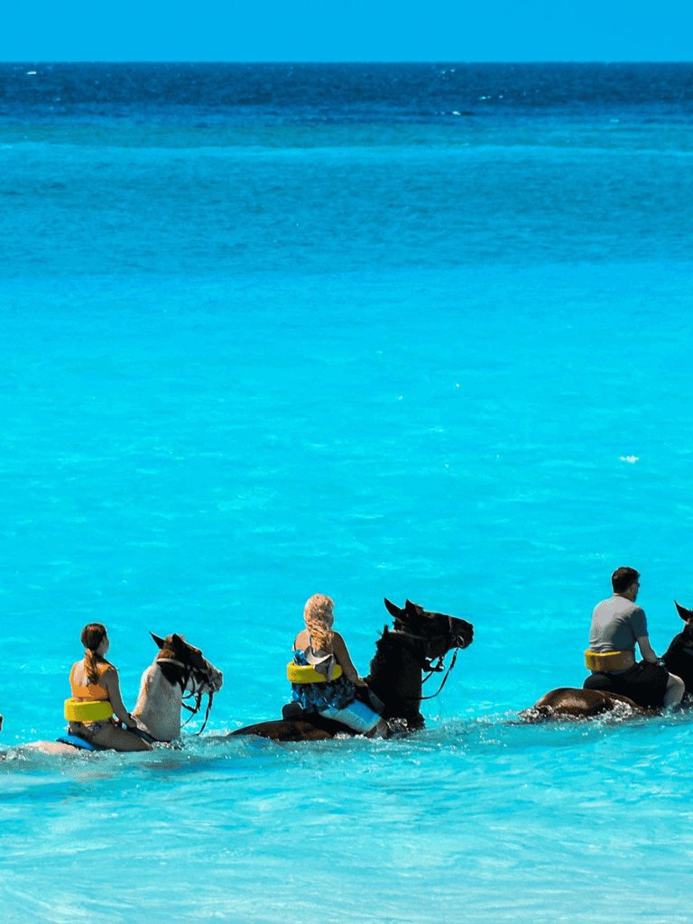 Kids riding horses in ocean water for a unique beach adventure.