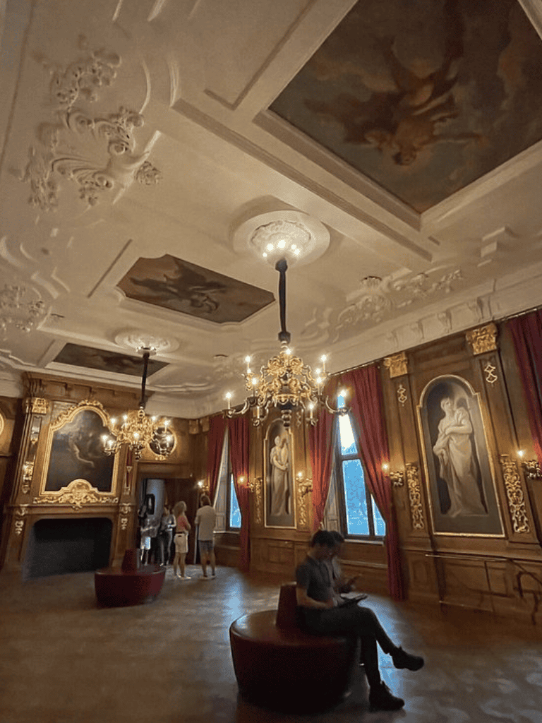 Elegant historic interior with ornate chandeliers and classical artwork, ideal for luxury event venues and cultural experiences.