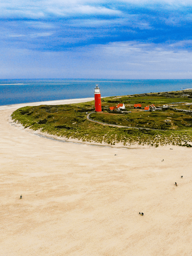 Seaside lighthouse on green island with sandy beach and ocean background.