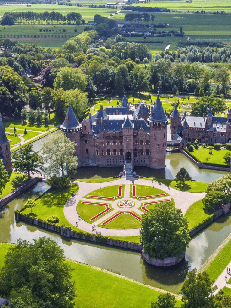 Fairytale castle surrounded by lush gardens and moat, scenic countryside views, and historic architecture.