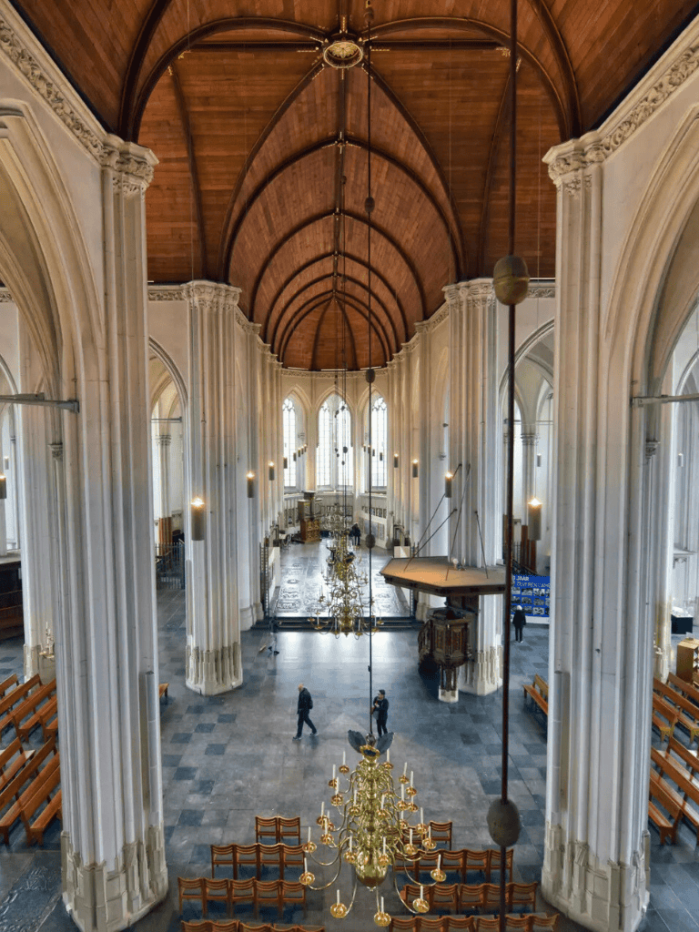 Elevated view of historic church with grand wooden vaulted ceiling and elegant chandeliers.