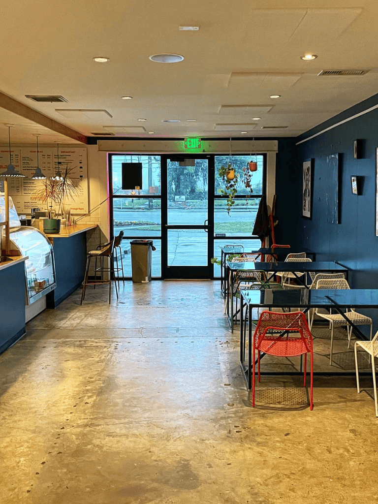 Bright cozy cafe interior with seating, counter, and large front door for restaurant ambiance.