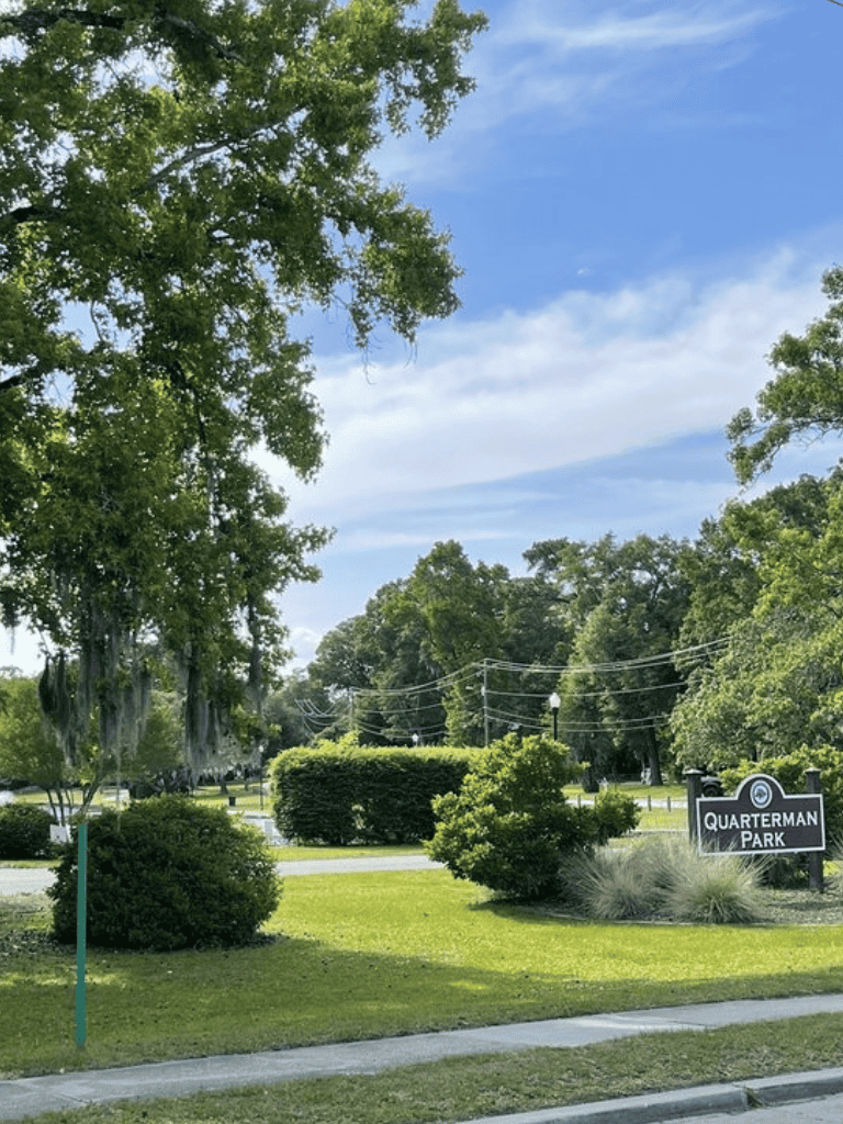 Lush park with trees and shrubs at Quarterman Park under a partly cloudy sky.