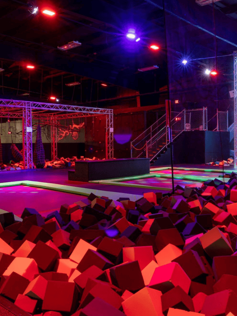Colorful indoor trampoline park with foam pits, lighting effects, and adventure zones for all ages.