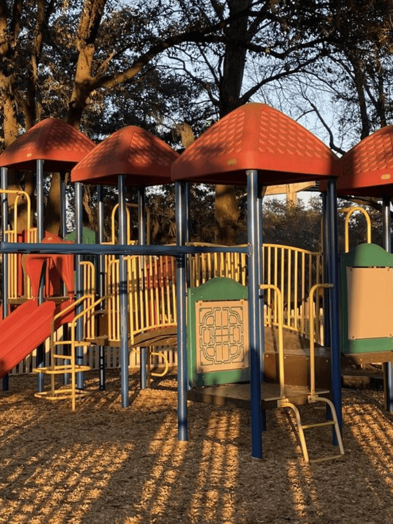 Colorful playground structure with slides and climbing features in outdoor park setting.