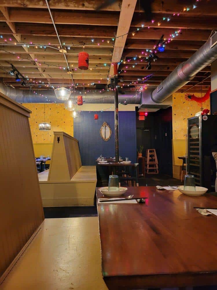 Colorful restaurant interior with fairy lights, wooden furniture, and decorative red lanterns, creating a cozy dining atmosphere.