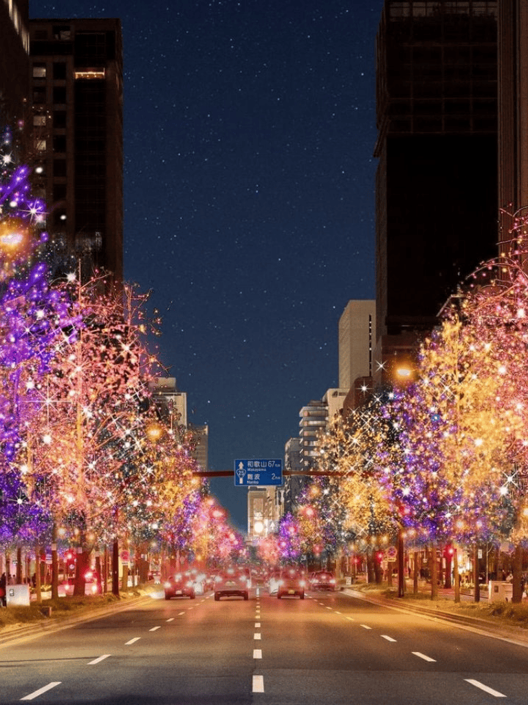 Festive city street at night with colorful Christmas lights and decorated trees, holiday season ambiance.