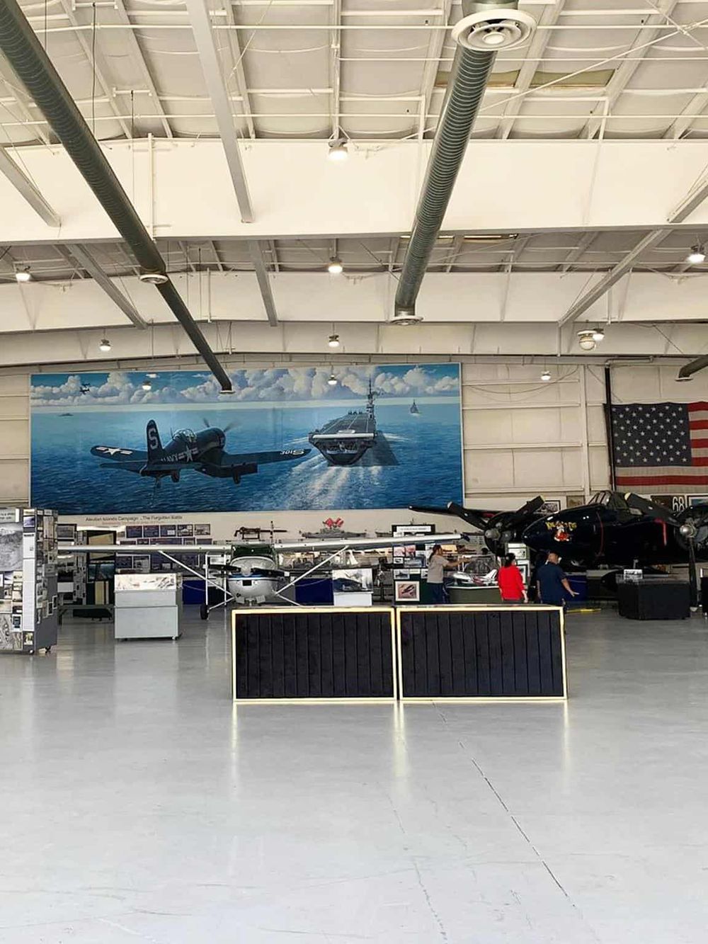 Outdoor military aviation museum exhibits featuring vintage aircraft and a WWII aircraft mural.