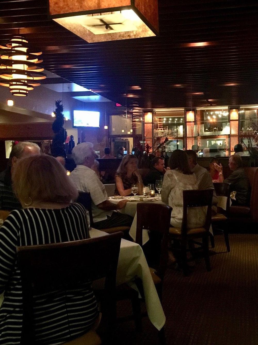 Cozy restaurant interior with diners enjoying dinner and a large bar area, perfect for exploring dining options with QuestForDirections.