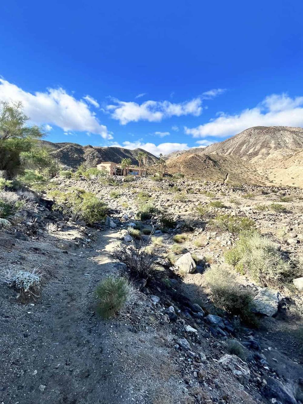 Rustic desert trail with mountains and clear blue sky, ideal for outdoor adventure and navigation.
