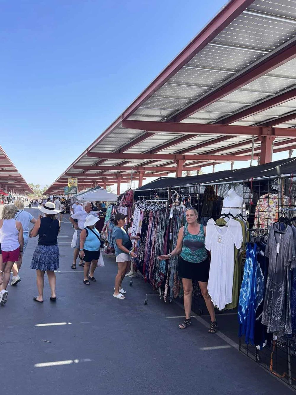 Vintage outdoor market with clothing stalls and shoppers, sunny day, QuestForDirections.