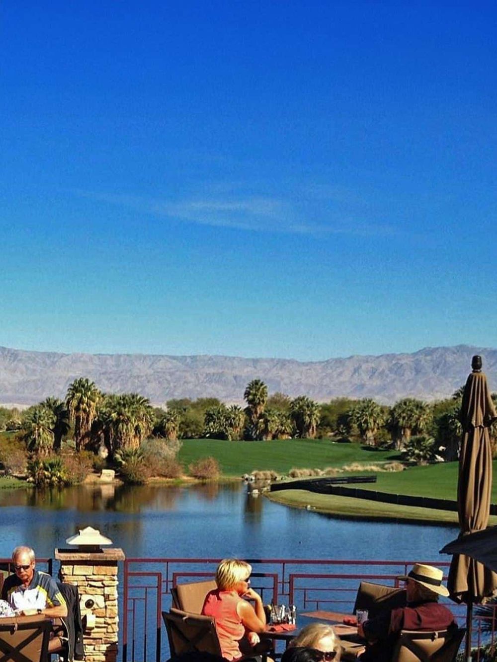 Scenic golf course with palm trees, water hazard, and mountain backdrop, perfect for outdoor sports and relaxation.
