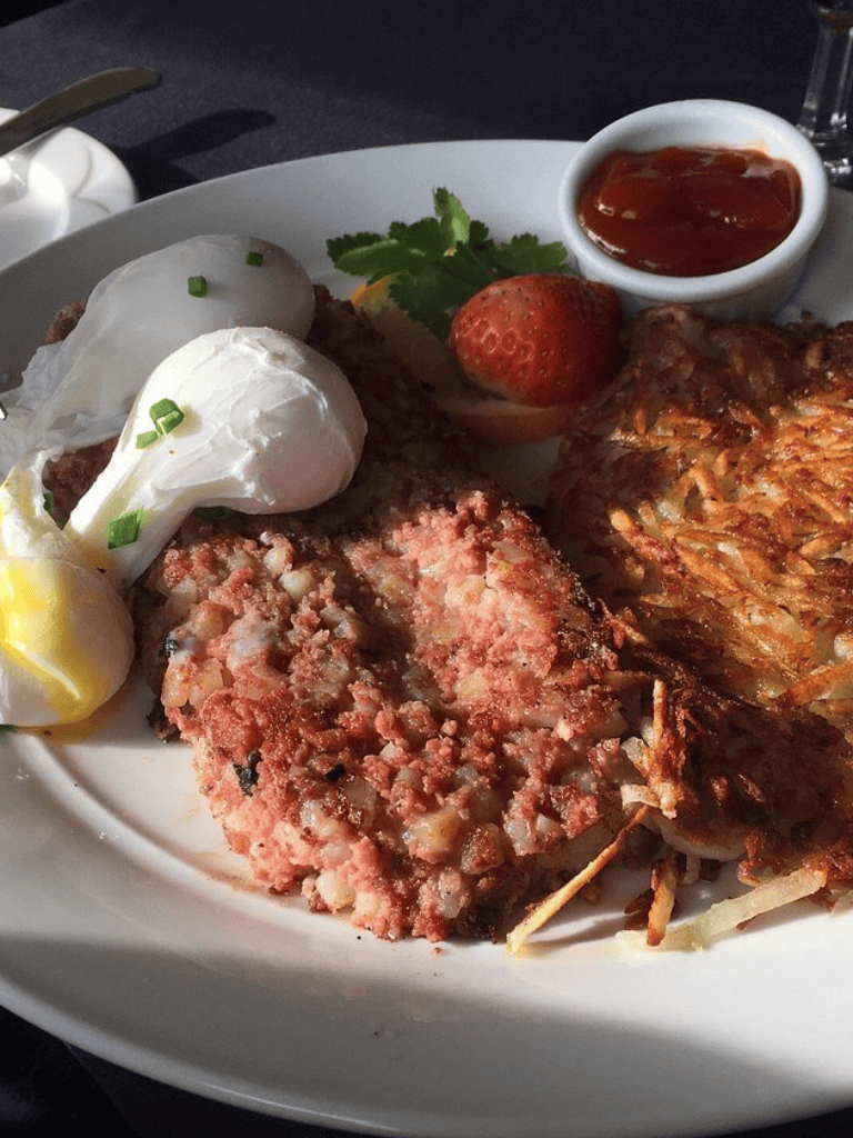 Savory breakfast plate with eggs, steak, hash, strawberries, and breakfast sauce, perfect for a hearty start.