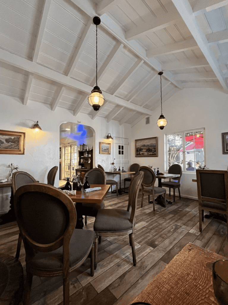 Cozy restaurant interior with rustic wooden furniture and hanging pendant lights, perfect for a relaxing dining experience.